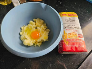Puree ziemniaczane, jajko i mąka w misce, gotowe do połączenia.