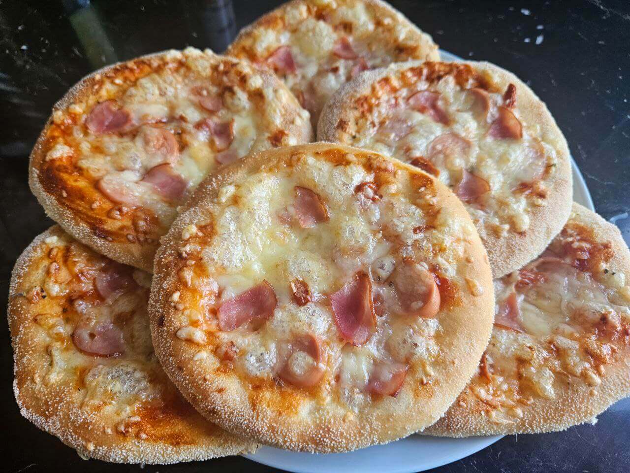 Mini pizze: Gotowe, złociste mini pizze z ciągnącym się serem i szynką to idealna przekąska.