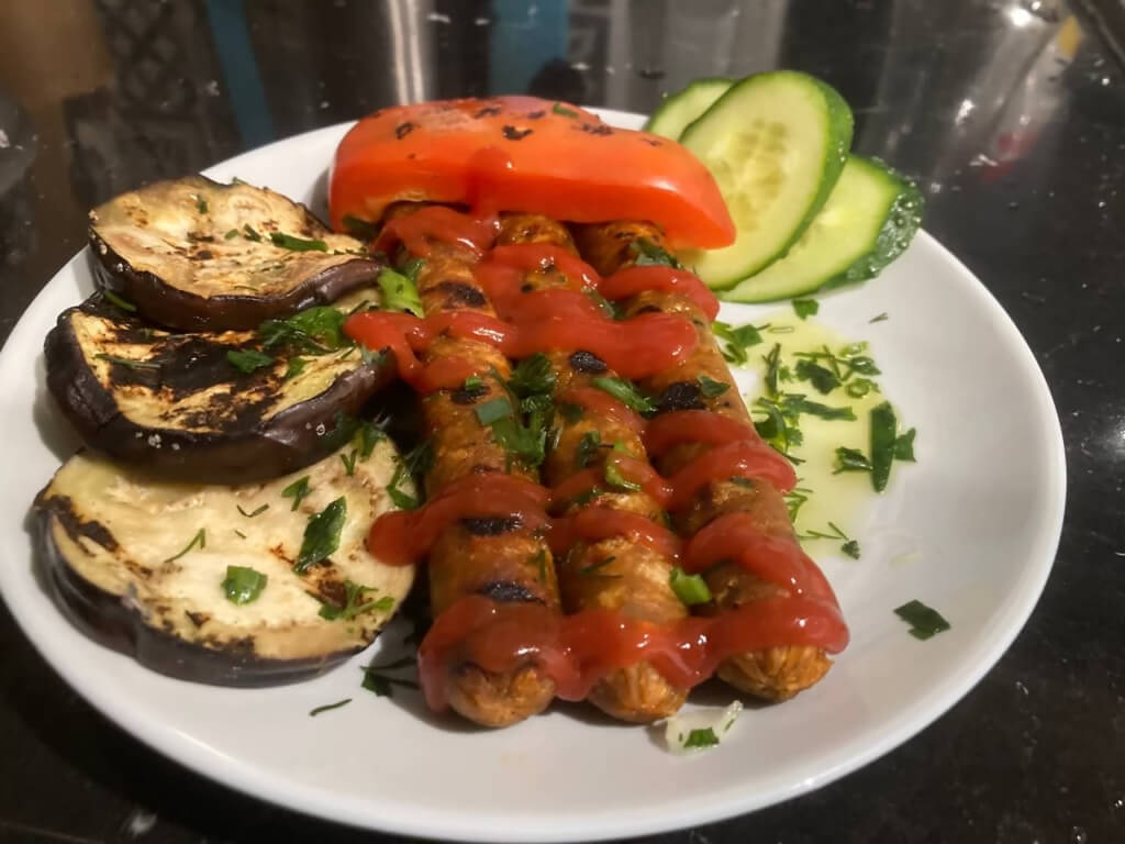 Talerz z grillowanymi warzywami i roślinnymi kiełbaskami – inspiracja na Co na grilla bez mięsa.