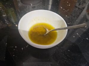 Przygotowanie sosu w miseczce, który uzupełnia przepis na szybką sałatkę z tuńczyka i świeżych warzyw.