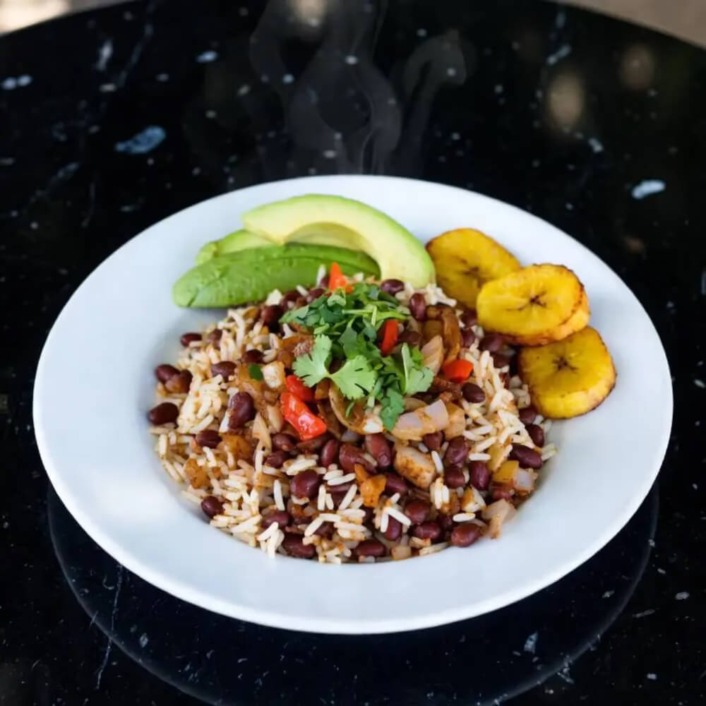 Kuchnia wegetariańska w Nikaragui – wegańskie gallo pinto z ryżem, czerwoną fasolą, awokado i smażonymi bananami plantain na czarnym marmurowym stole Kuchnia wegetariańska w Nikaragui