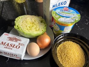 Składniki na danie kapusta zasypana z kaszą jaglaną na czarnym blacie kuchennym