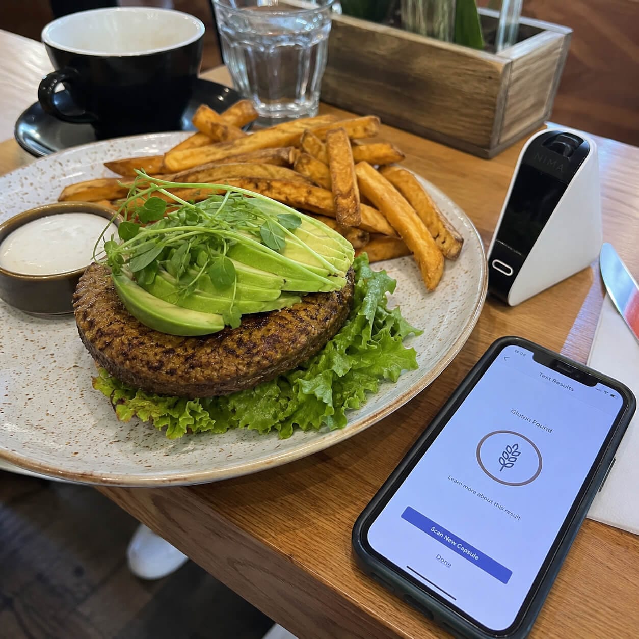 Nima w restauracji podczas testowania bezglutenowego burgera z frytkami pod kątem ukrytego glutenu i zanieczyszczeń krzyżowych