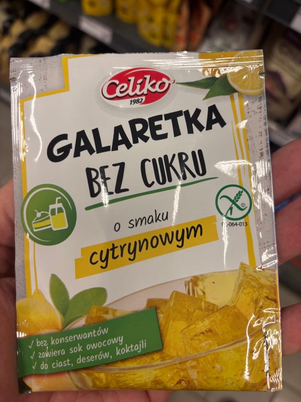 Jasne opakowanie galaretki bez cukru Celiko o smaku cytrynowym z grafiką plastra cytryny, kostek żółtej galaretki oraz zielonym symbolem Przekreślonego Kłosa.