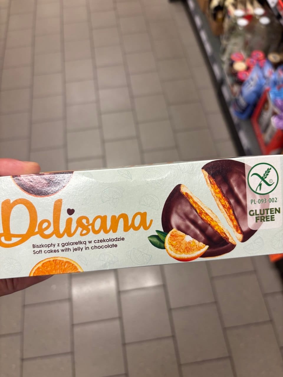 Opakowanie ciastek Delisana Biszkopty z galaretką w czekoladzie o smaku pomarańczowym z grafiką owoców, przekrojonych ciastek oraz zielonym logo Gluten Free.