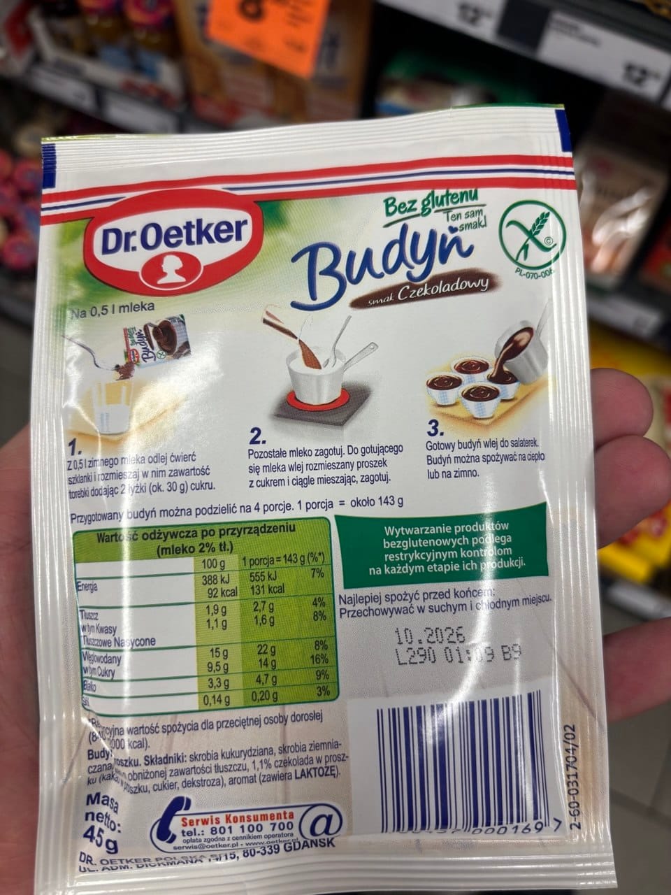 Tył opakowania budyniu czekoladowego Dr. Oetker Bez glutenu z trzyetapowym opisem przygotowania, tabelą wartości odżywczych, zielonym logo Przekreślonego Kłosa i kodem kreskowym.