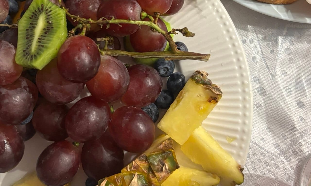 A white plate filled with fresh, naturally gluten-free and vegan fruits like pineapple, grapes, and kiwi, representing safe breakfast options in Sri Lanka.