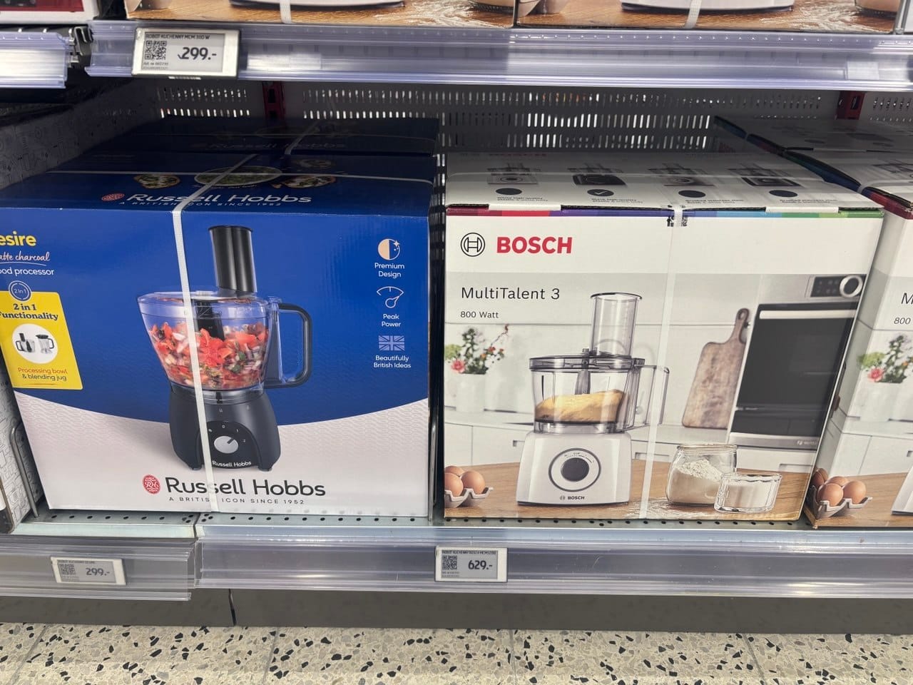 Pudełka z robotami kuchennymi marek Russell Hobbs i Bosch na sklepowej półce, przydatne do przygotowywania dań w kuchni roślinnej i bezglutenowej.