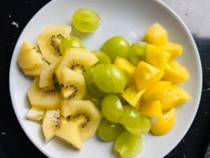 Pokrojone w kostkę pepino, plastry kiwi i połówki zielonych winogron na białym talerzu