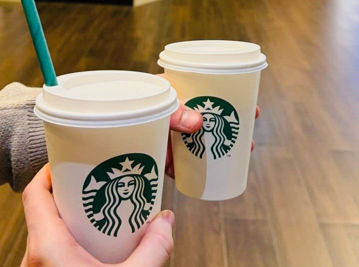Dwie papierowe kawy na wynos ze Starbucks w dłoniach, jako propozycja na bezpieczny napój podczas bezglutenowej podróży i szukania miejsc z oferty Ankara bez glutenu