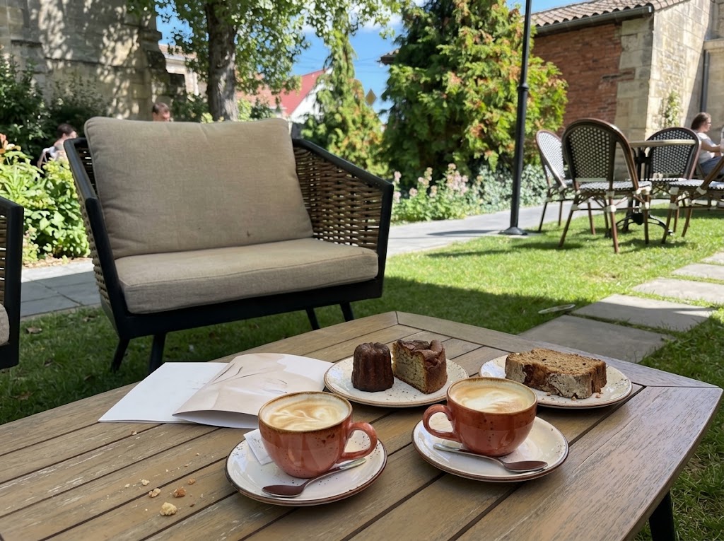 Two cups of vegan coffee and gluten-free pastries on a wooden table in a sunny Bordeaux courtyard.